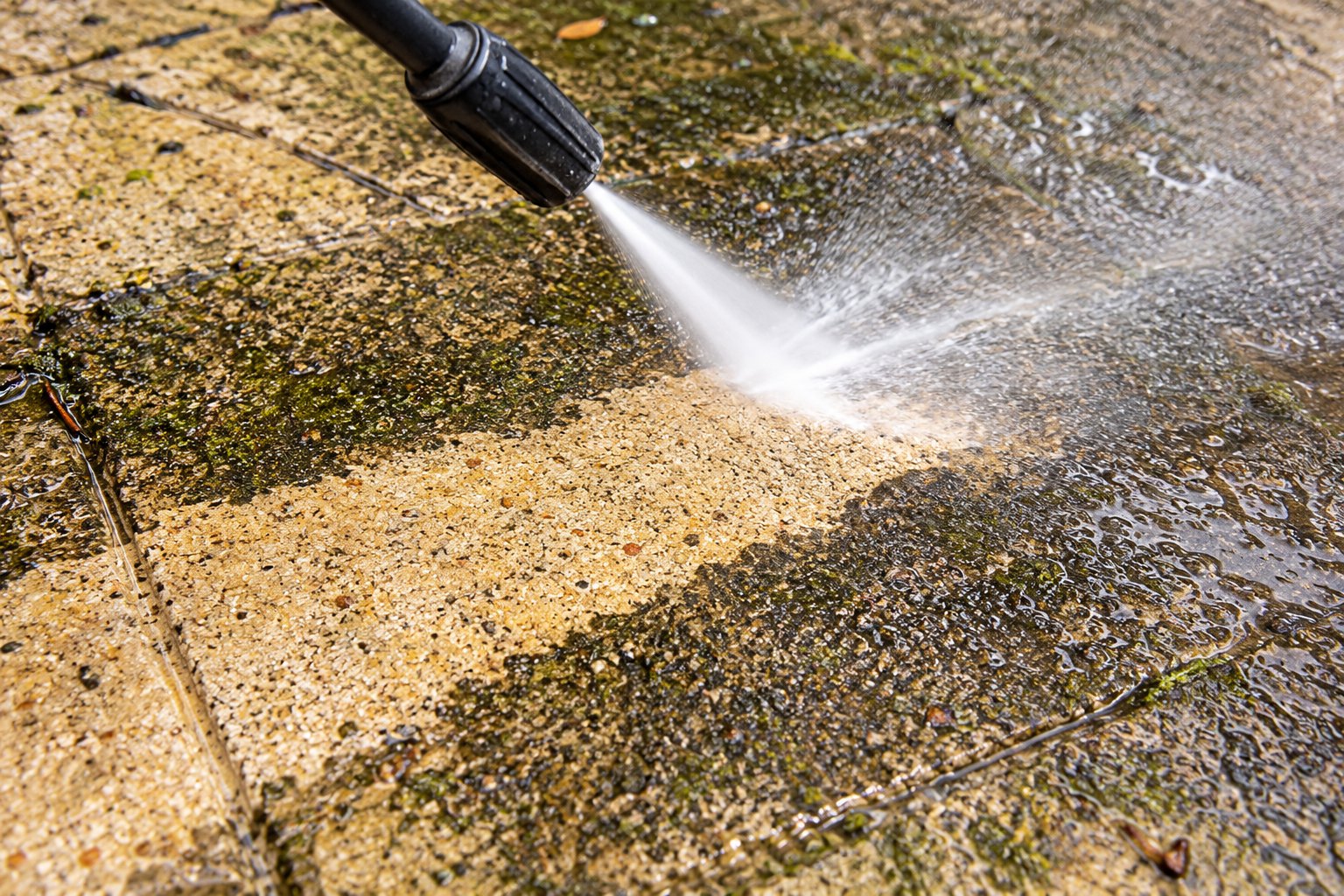 Close-up of a pressure cleaning nozzle lifting grime from concrete