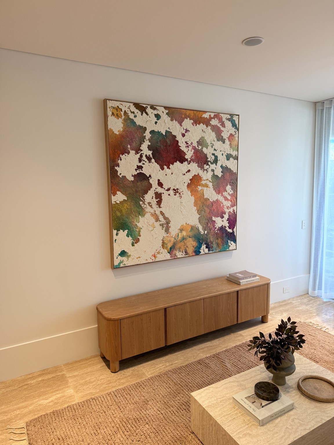 Large abstract artwork installed above a timber console